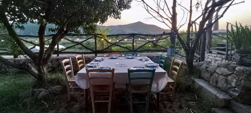 Una mesa vestida para comer entre los arboles del Agroturismo Fustanella y las vistas de la montaña.