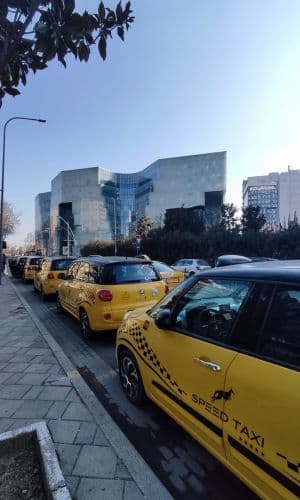 Taxis amarillos frente a un edifico vanguardista.