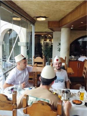 Albaneses con sus gorros tradicionales comiendo en restaurante panorama